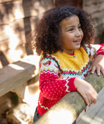 A child wearing the Frugi Festive Fair Isle Organic Cotton Kids' Carol Cardigan featuring red, yellow and green patterns and robin redbreast details. 
This knitted cardigan is a part of a wide range of organic cotton clothing for children available here at Babipur.