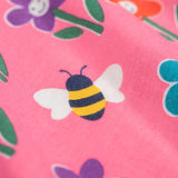 A close up of the print detail on the Frugi Sofia skater dress with a fun flowers design on a tulip pink background.