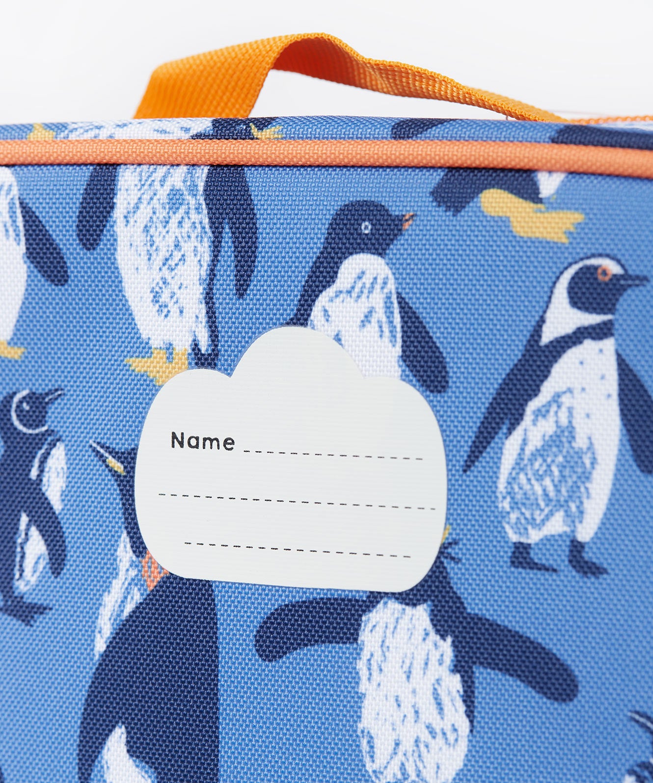 A close up of the Frugi kids pack a lunch bag in penguin waddle. Showing the name tag patch detail and orange trim