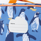 A close up of the Frugi kids pack a lunch bag in penguin waddle. Showing the name tag patch detail and orange trim