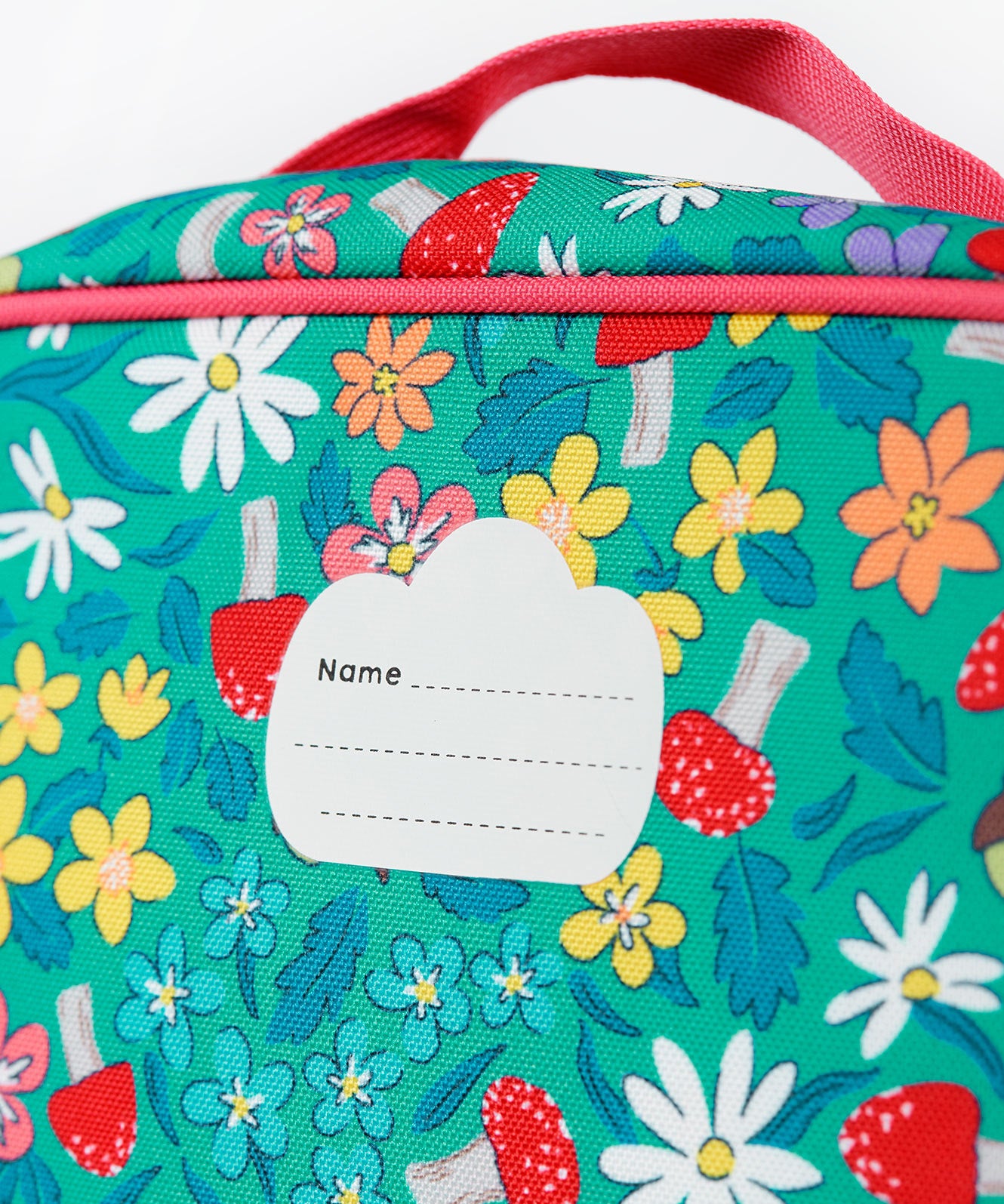 A close up of the Frugi kids pack a lunch bag in wild woods. Showing the name tag patch detail and pink trim