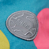 A close up of the orange arm of the Frugi super spot  parka showing the circular brand patch stitched on the top of the arm on organic cotton fabric