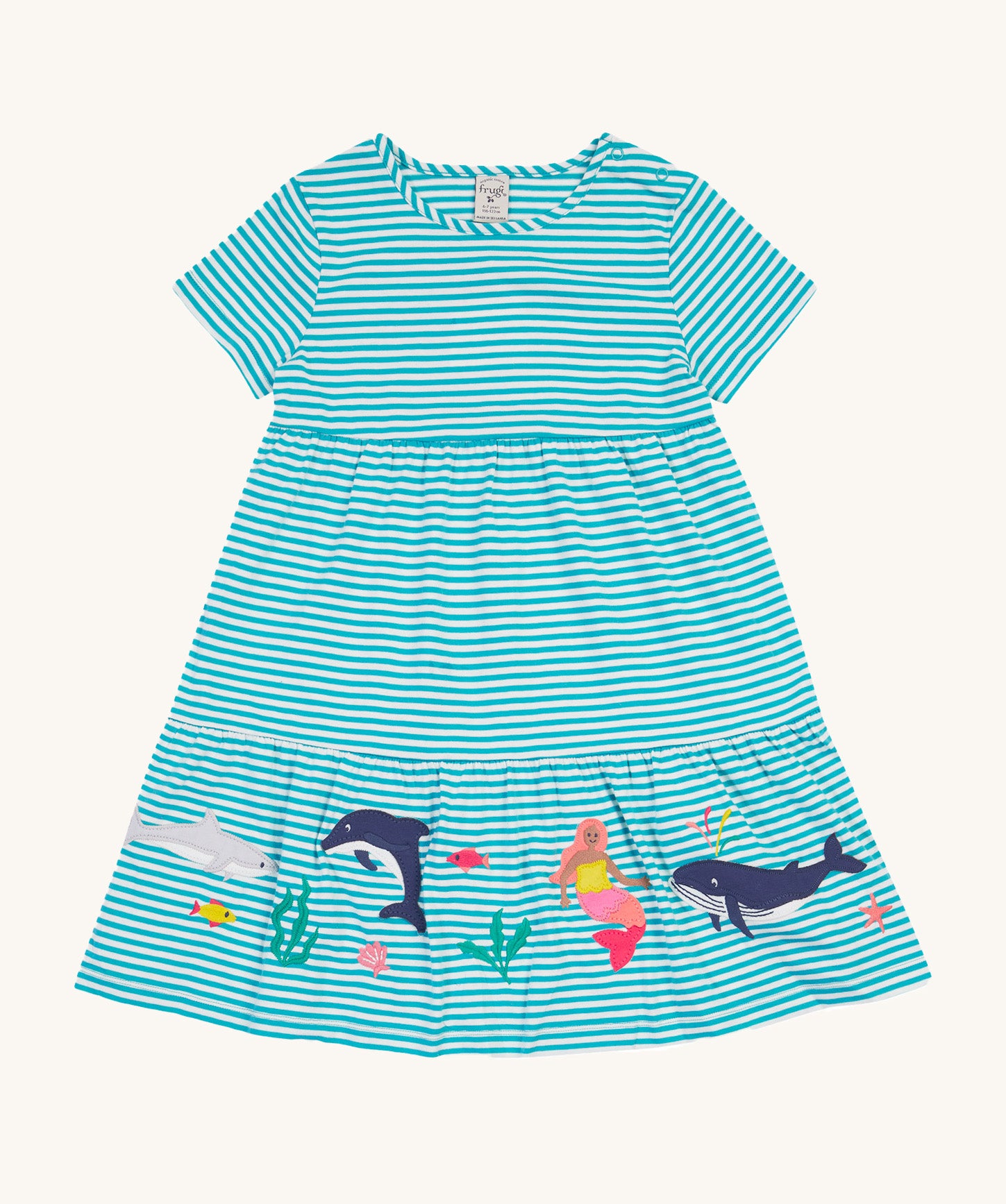 Frugi Pixy Sea Moss Mini Stripe Dress laid flat, with a Sealife print along the bottom, featuring whales, dolphins, sharks, a Mermaid and some small fish, surrounded by colorful seaweed.