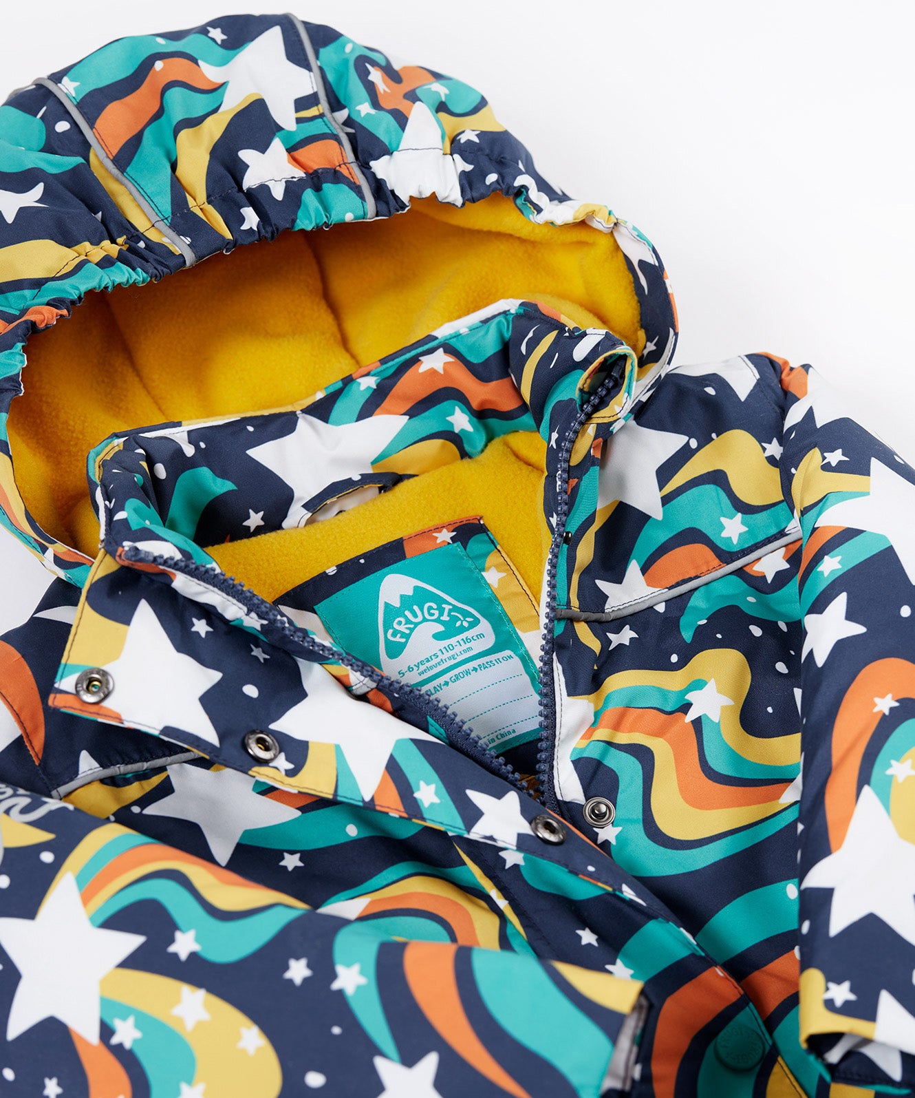 A close up of the Frugi kids playtime coat in magic stars. Showing the zip and name tag detail on the outer space inspired print.