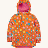 Frugi kids puddle buster coat in fun flowers. A orange waterproof hooded coat with multiple playful prints of flowers with faces and a pink fleece on the inside. Features 2 side pockets, reflective strips on the wrist cuffs and a hook on the inside to hang up.