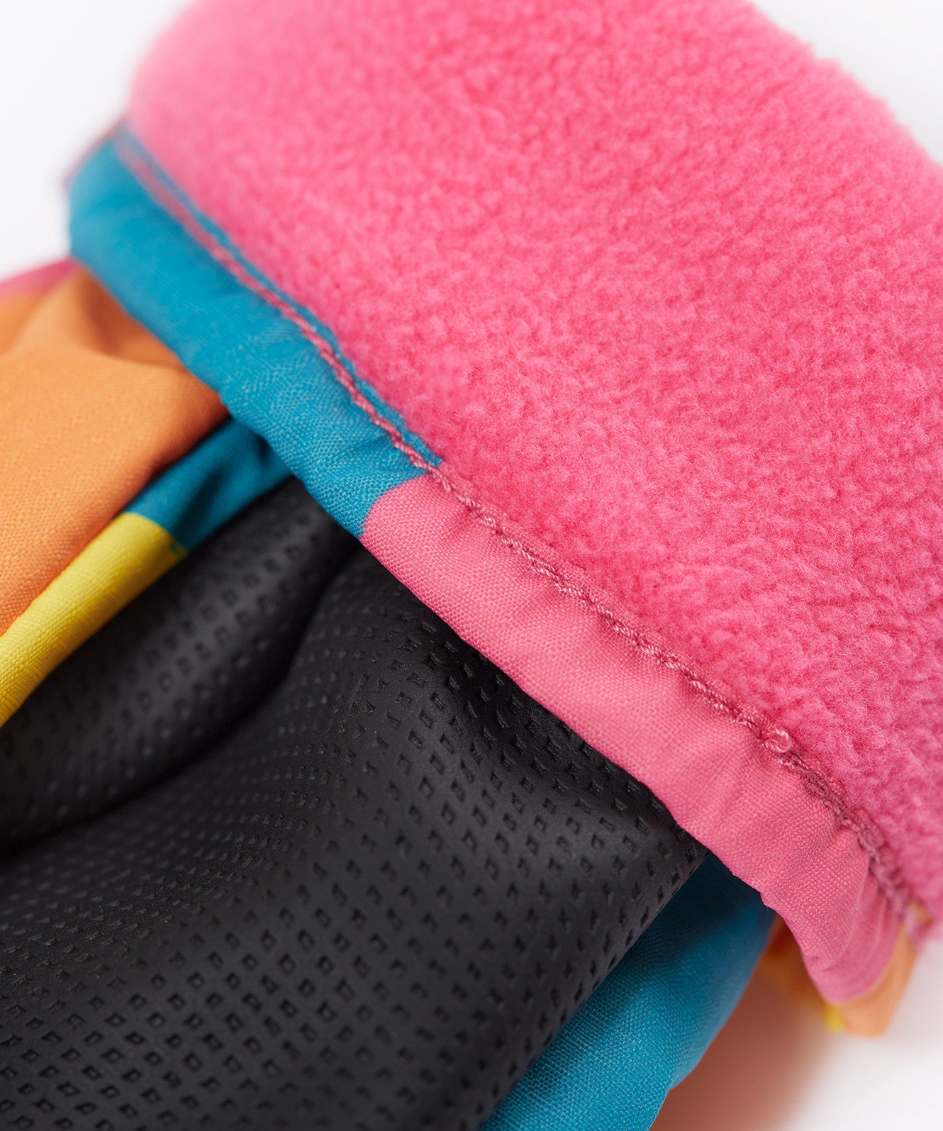 A close up of the Frugi kids rainbow check snow mittens showing the black grippy palm and pink fleece inner for warmth