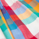 A close up of the multicoloured material of the Frugi Rainbow Check Organic Cotton Ffion Dress. The dress has a rounded collar details and button closure on the front. This festive kids dress is a part of a wide range of organic cotton clothing for children available here at Babipur.