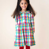 A child wearing the Frugi Rainbow Check Organic Cotton Ffion Dress. The dress has a rounded collar details and button closure on the front. This festive kids dress is a part of a wide range of organic cotton clothing for children available here at Babipur.