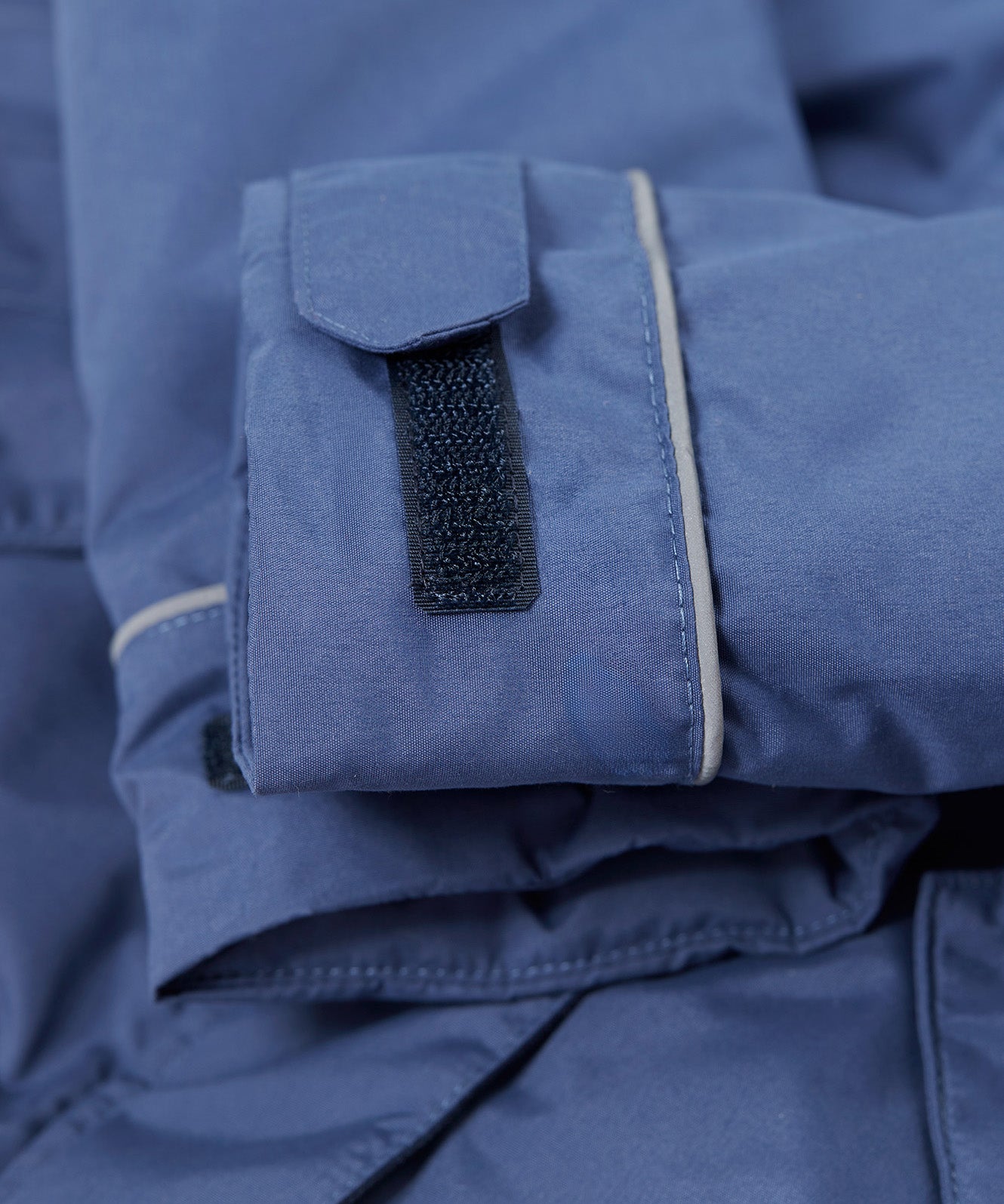 A close up of the Frugi kids 3 in 1 rambler coat in Autumn stripe /navy colourway showing the velcro detail on the arm for size adjusting.