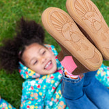 A child wearing the Frugi Ravine easy on children's leather boots in a brown, wild woods design showing the ruber soles on the shoes.