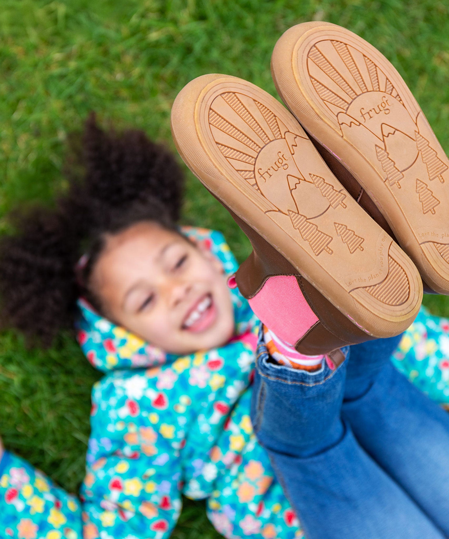 A child wearing the Frugi Ravine easy on children's leather boots in a brown, wild woods design showing the ruber soles on the shoes.