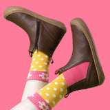 A child wearing the Frugi Ravine easy on children's leather boots in a brown, wild woods design with yellow dotted socks.