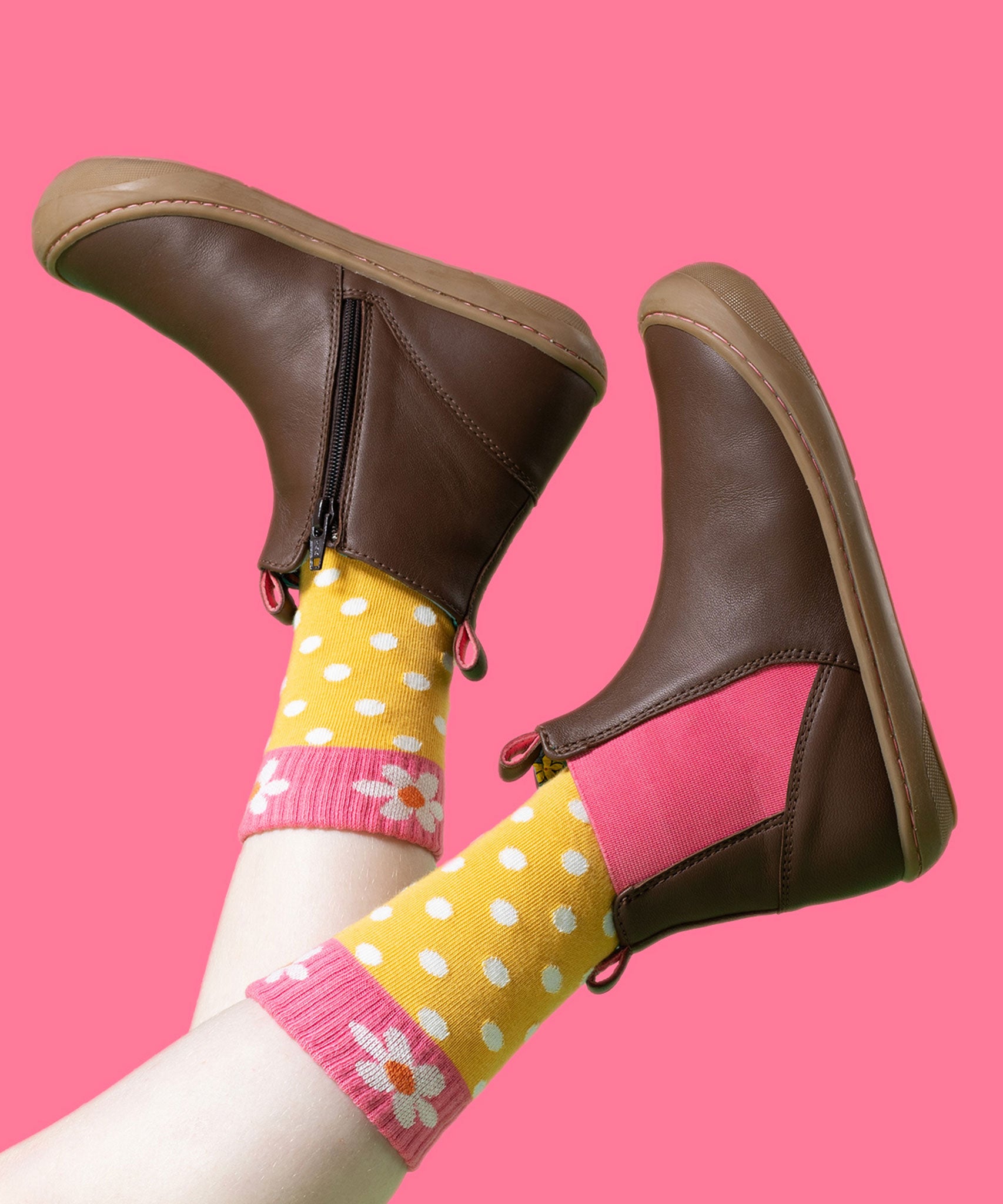 A child wearing the Frugi Ravine easy on children's leather boots in a brown, wild woods design with yellow dotted socks.