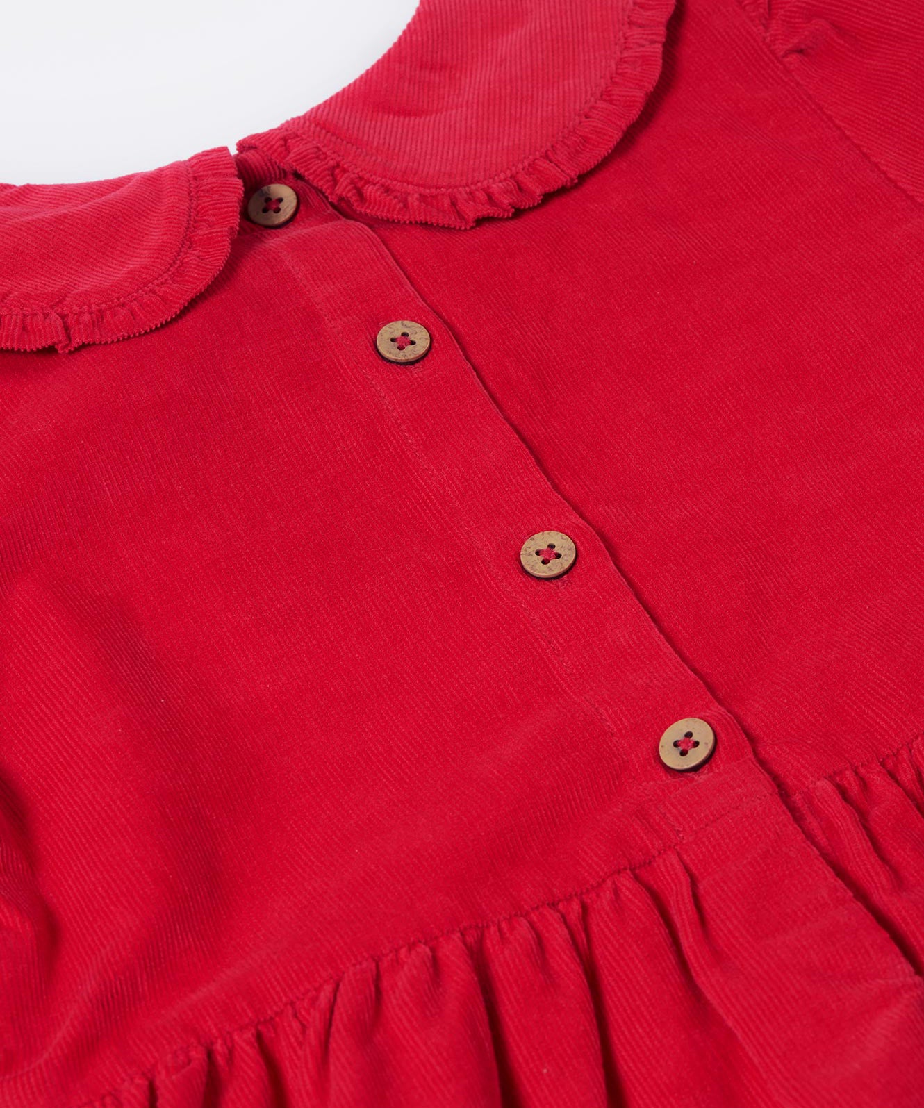 A close up of the button closure on the back of the Frugi Red Robin Corduroy Kids' Christmas Organic Dress. This red cord dress is a part of a wide range of organic cotton clothing for children available here at Babipur.