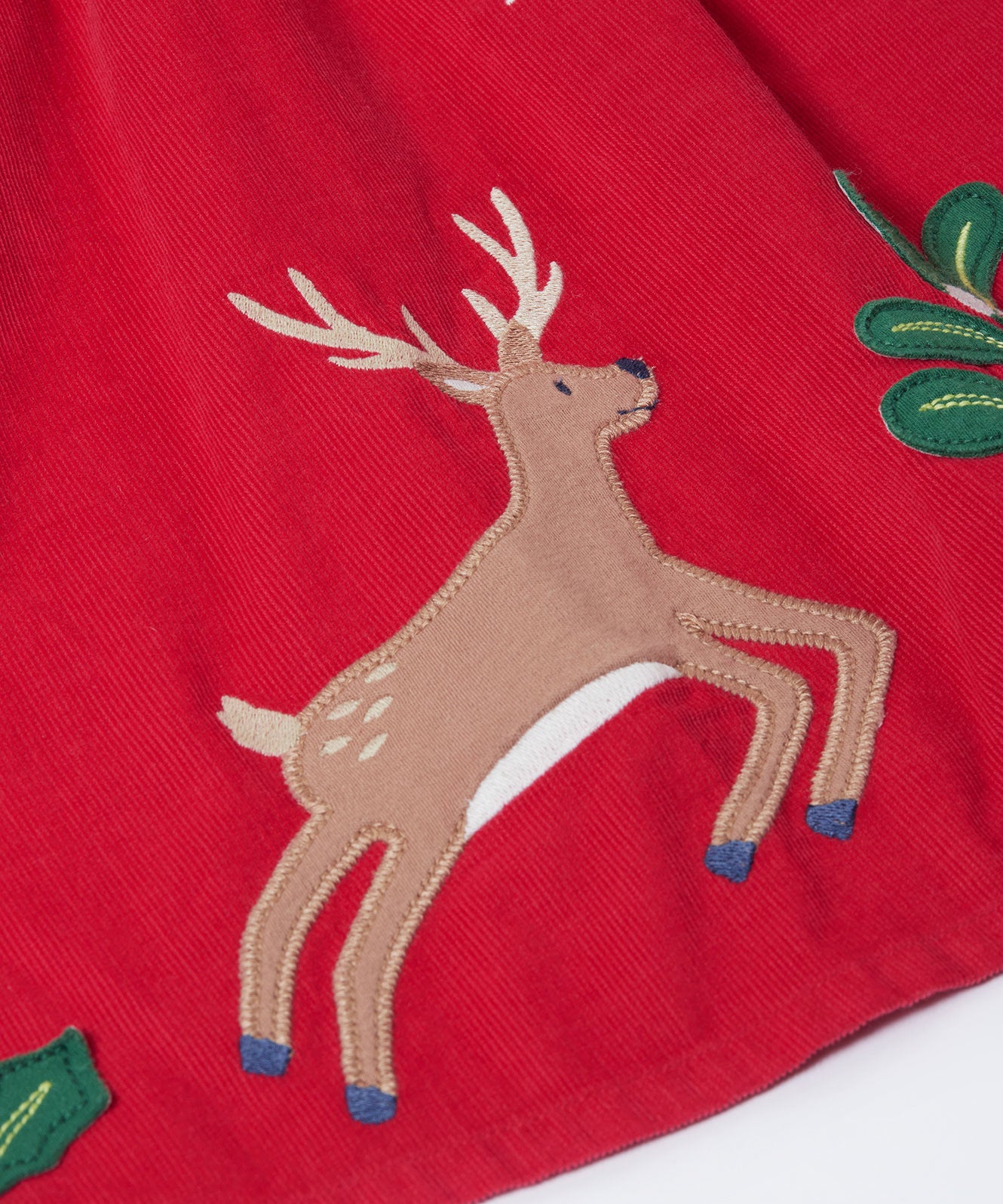 A close up of the reindeer applique on the front of the Frugi Red Robin Corduroy Kids' Christmas Organic Dress. This red cord dress is a part of a wide range of organic cotton clothing for children available here at Babipur.