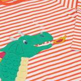 A close up of the fire breathing dragon on the front of the Frugi Salamander Stripe Dragon Discovery Circular Top. This orange and white striped top has a green coloured dragon applique detail on the front. This top is a part of a wide range of organic cotton clothing for children available here at Babipur.