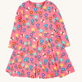 The Frugi Sofia skater dress with a fun flowers design on a tulip pink background. The dress has long sleeves.