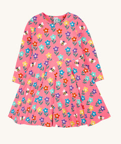The Frugi Sofia skater dress with a fun flowers design on a tulip pink background. The dress has long sleeves.
