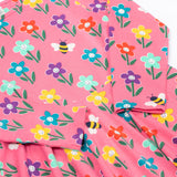 A close up view of the Frugi Sofia skater dress with a fun flowers design on a tulip pink background.