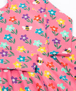A close up view of the Frugi Sofia skater dress with a fun flowers design on a tulip pink background.