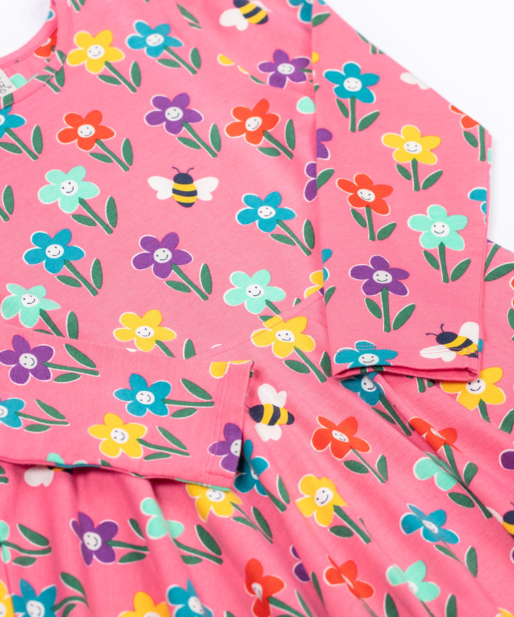 A close up view of the Frugi Sofia skater dress with a fun flowers design on a tulip pink background.