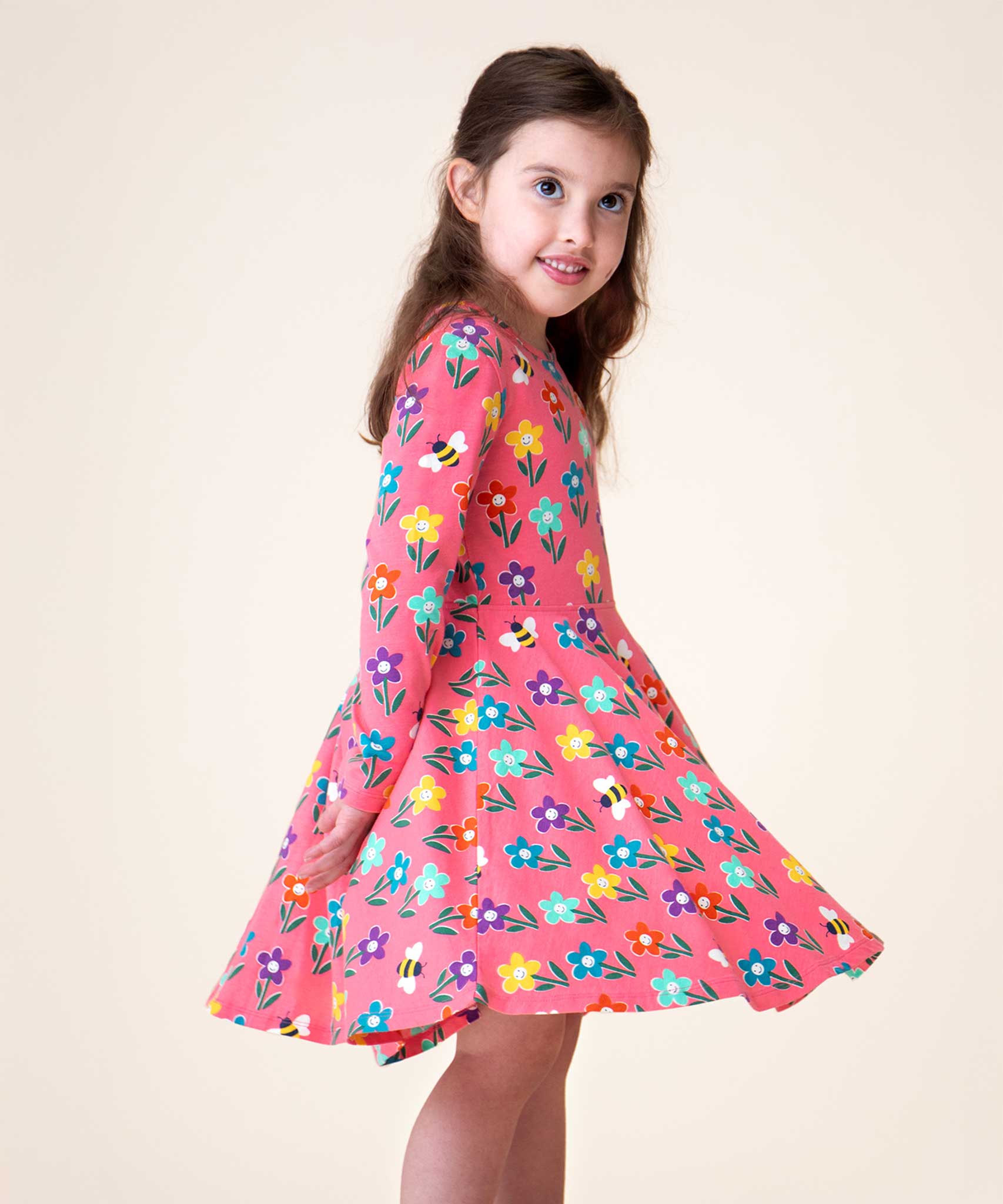 A child wearing the Frugi Sofia Pink fun flowers print skater dress.