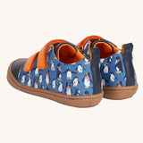 A view of the back of the Frugi Penguin Print Tide Low Top velcro closure leather children's shoes. There is a navy blue strip at the back with a pull tab attached to it for easy on and offs.