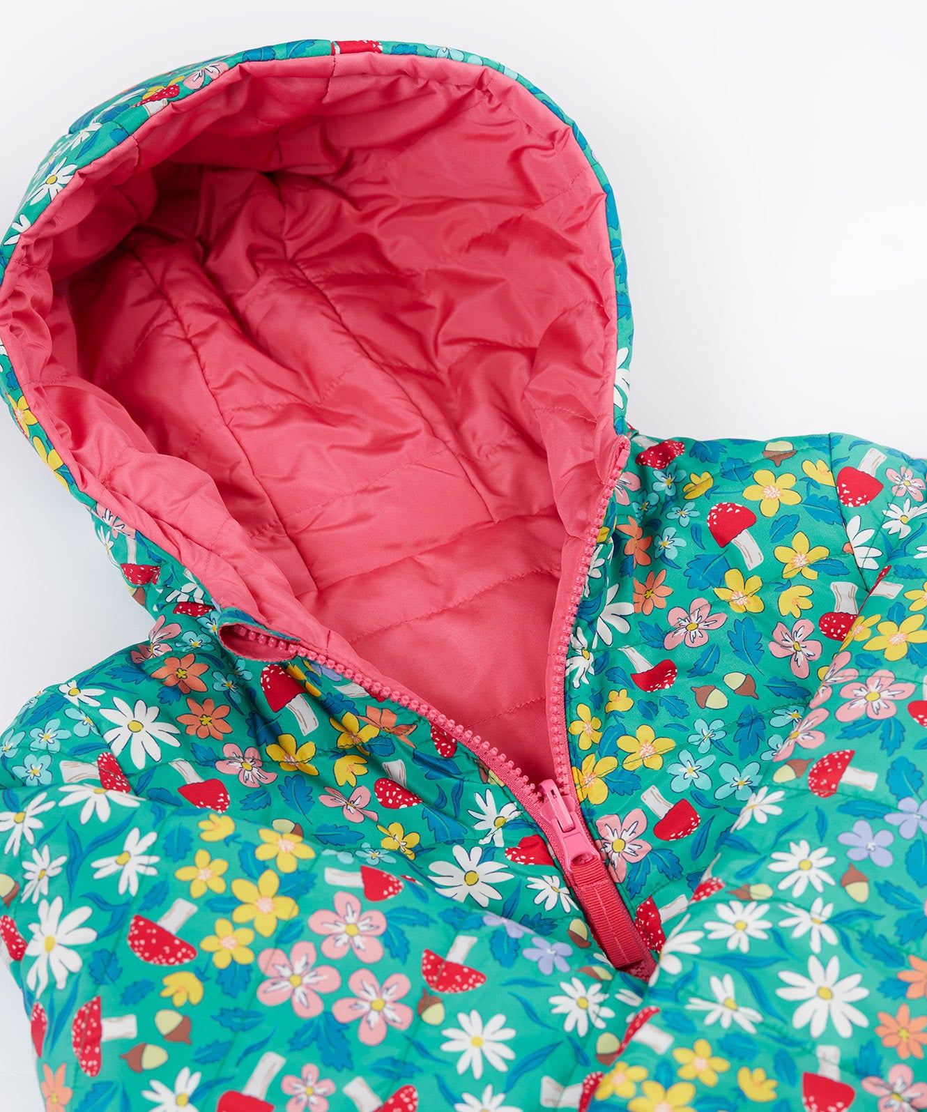 A close up of the Frugi toasty trail reversible jacket showing the playful woodland inspired design with pink zip and hood detail.