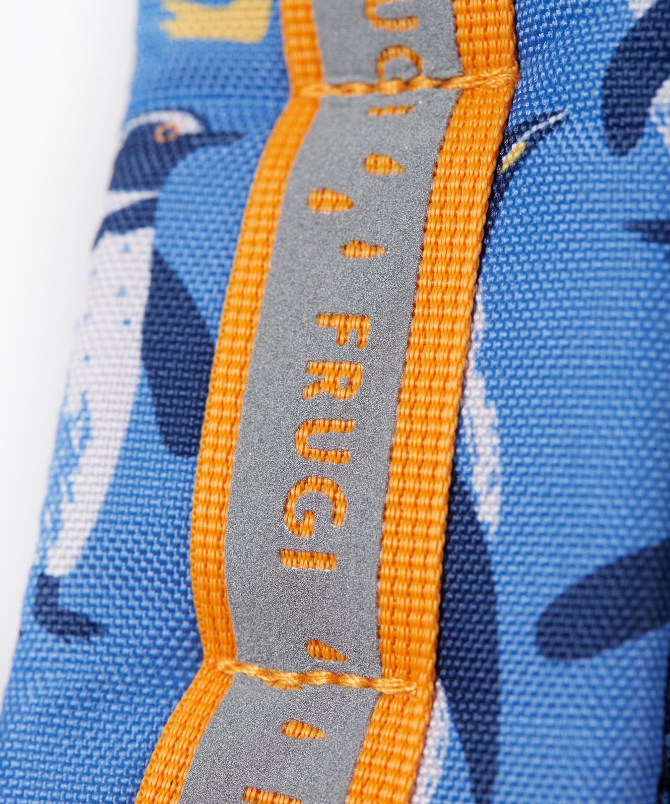 A close up of the shoulder strap on the Frugi kids trail blazing backpack in penguin waddle. Showing the reflective strip running down the strap