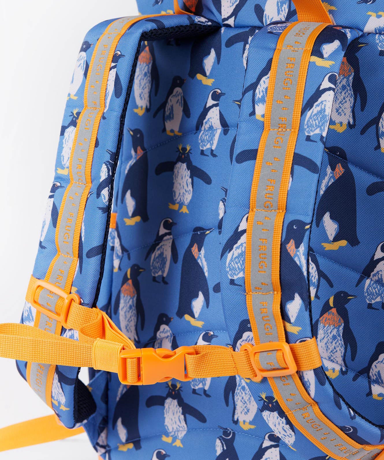A close up of the Frugi kids trail blazing backpack in penguin waddle. Showing the shoulder strap detail and orange chest buckle connecting the shoulder straps