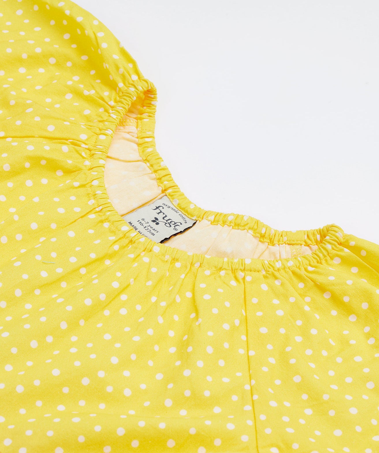 A close up of Frugi Dorothy Twirly Dress in its Rainbow Hotchpotch print, featuring a spotty yellow design.