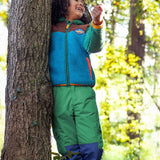 A child wearing the Frugi Wilderness green trousers with navy blue coloured knee patches with a Frugi colour block fleece.