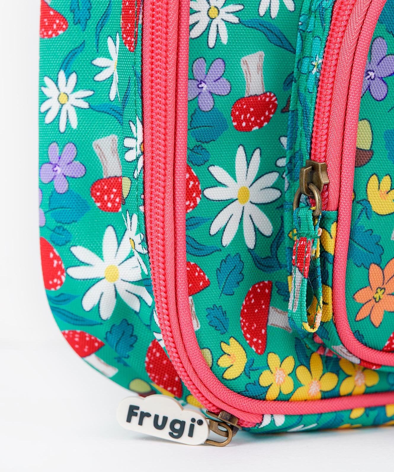 A close up of the Frugi kids pack a lunch bag in wild woods. Showing the pink trim and zip detail