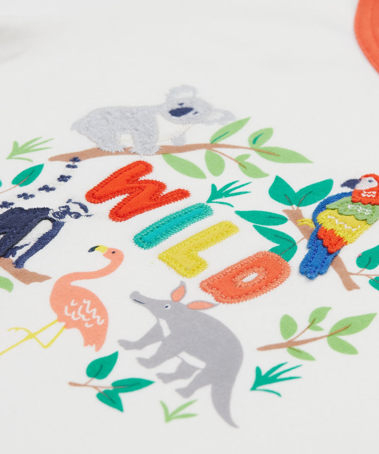 A close up of Frugi Xavier Circus T-Shirt in Soft White, featuring the word 'WILD' embroidered surrounded by exotic animals.