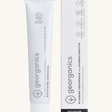 Front view of the Georganics activated charcoal hydroxyapatite toothpaste. A white tube with grey and black branding text next to matching cardboard packaging.