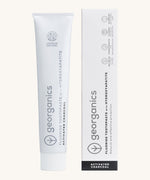 Front view of the Georganics activated charcoal hydroxyapatite toothpaste. A white tube with grey and black branding text next to matching cardboard packaging.