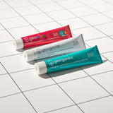 Georganics strawberry, activated charcoal and fresh mint toothpaste tubes on a white  and tile style floor.