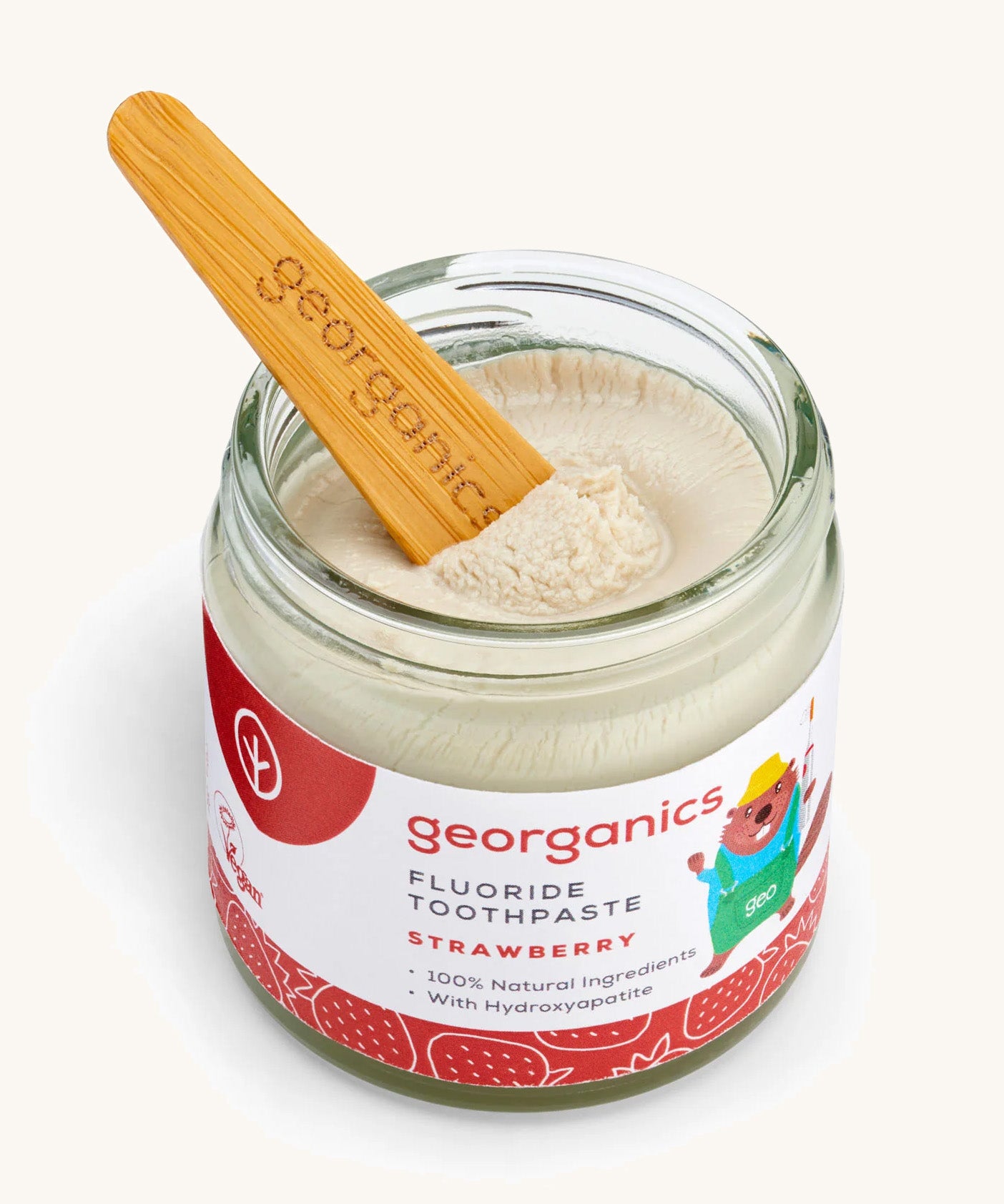 A opened jar of the strawberry fluoride toothpaste with a wooden spatula dipped in.