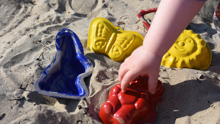 A child's hand playing with Gluckskafer metal outdoor toys