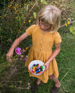Girl picking flowers and holding a bowl of Grapat wooden mandala mushrooms
