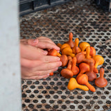 Close up of a child's hands reaching out to scoop up some Grapat wooden Waldorf mandala pumpkins