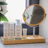 A collection of Green People facial care in a bathroom setting. The products are placed in a bamboo dish.