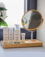 A collection of Green People facial care in a bathroom setting. The products are placed in a bamboo dish.