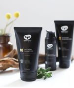 A tube of Green People no.10 Itch Away Shampoo placed on a white surface, there are ither products from the mens collection on the background.