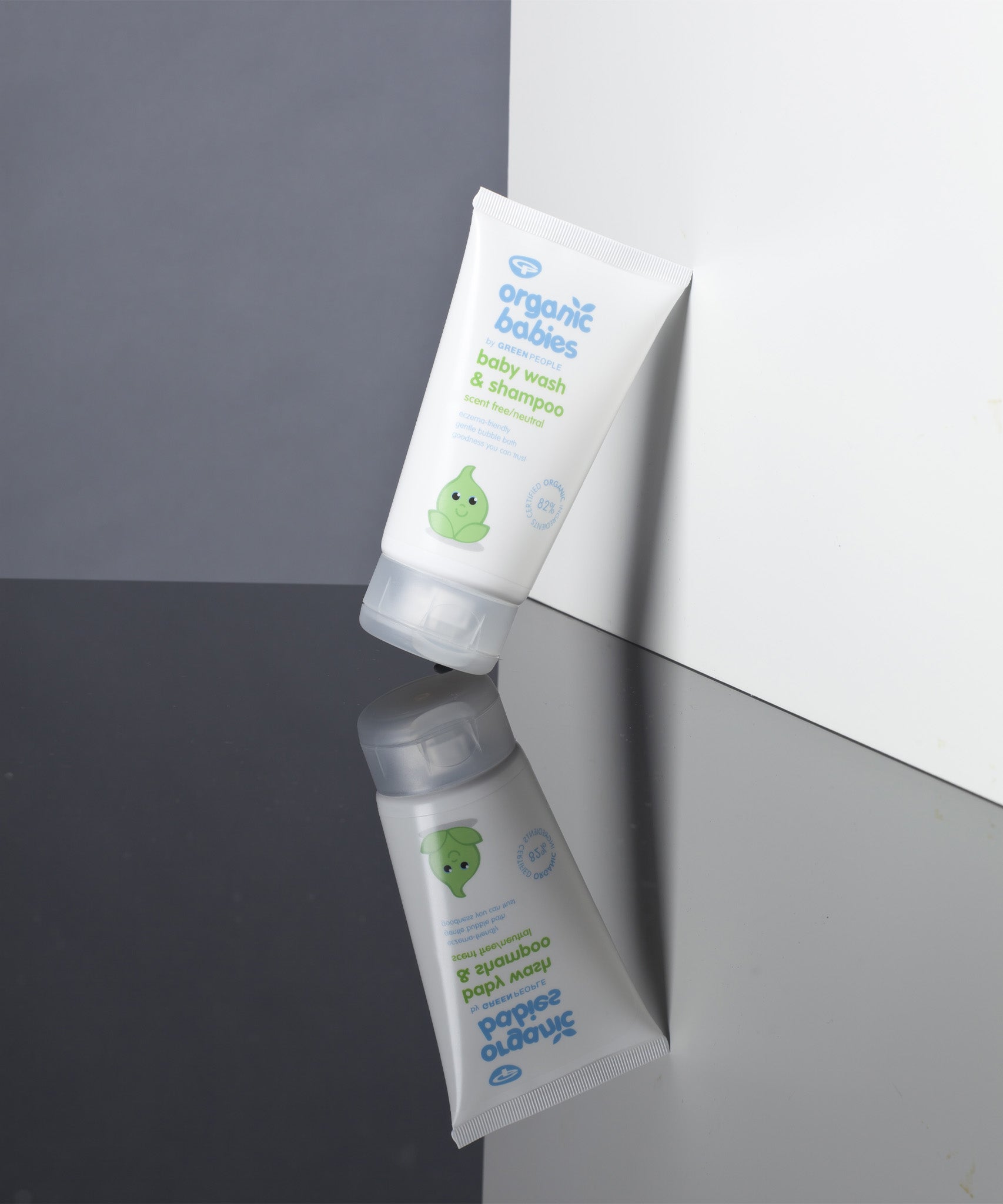 A tube of Organic Babies Baby Wash & Shampoo Scent Free placed on a mirrored surface.