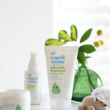 Organic Babies Baby Wash & Shampoo Scent Free placed on a white surface next to a wooden toy mouse. Other products from the organic babies collection can be seen in the background.