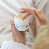 A close up of an adult's hand scooping some product out of the Organic Babies Mum & Baby Rescue Balm pot with their finger.