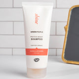 Green People Quinoa & Artichoke protein boost shampoo on a white surface in a bathroom.