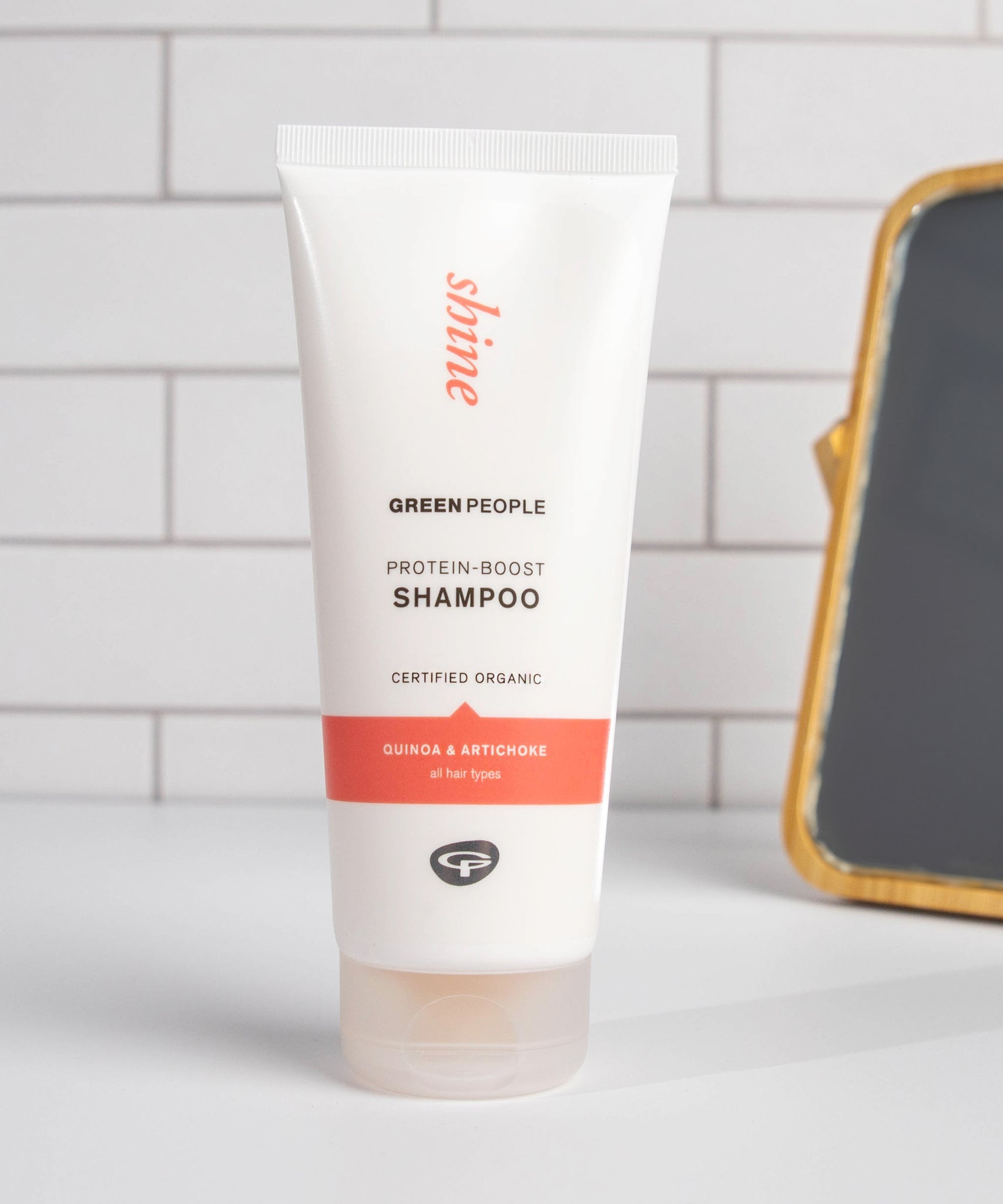 Green People Quinoa & Artichoke protein boost shampoo on a white surface in a bathroom.