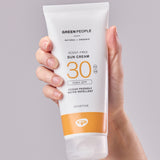 A tube of Green People Sun Cream SPF30 in an adult's hand.